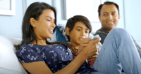 A family of 3 sitting on a mattress with an adjustable base